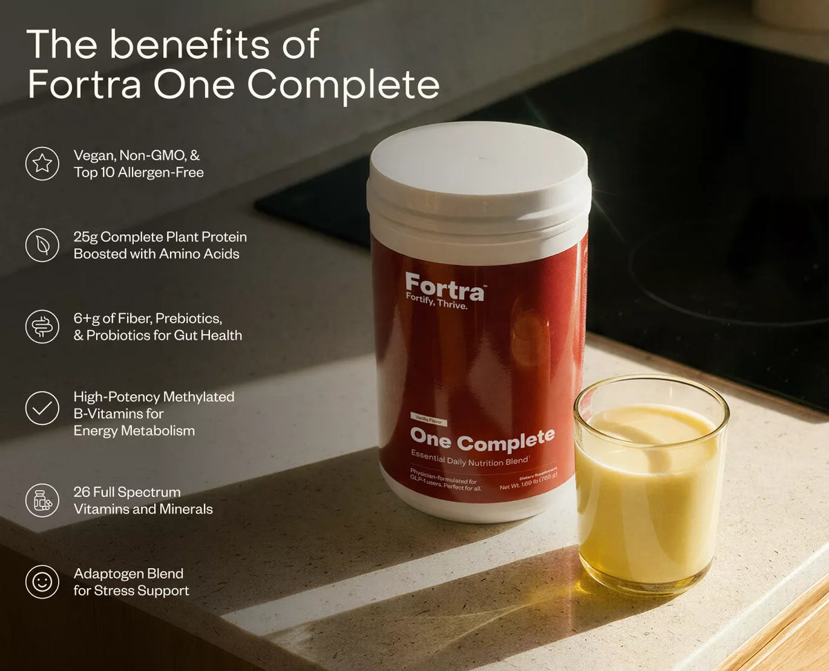 Fortra One Complete supplement container on a kitchen counter with a glass of liquid.